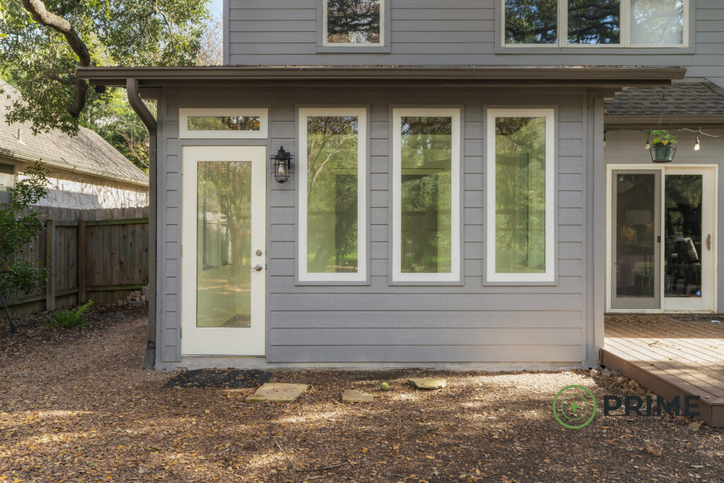 Austin custom home remodeling showcasing a modern gray home with new windows, glass door, and fresh renovations