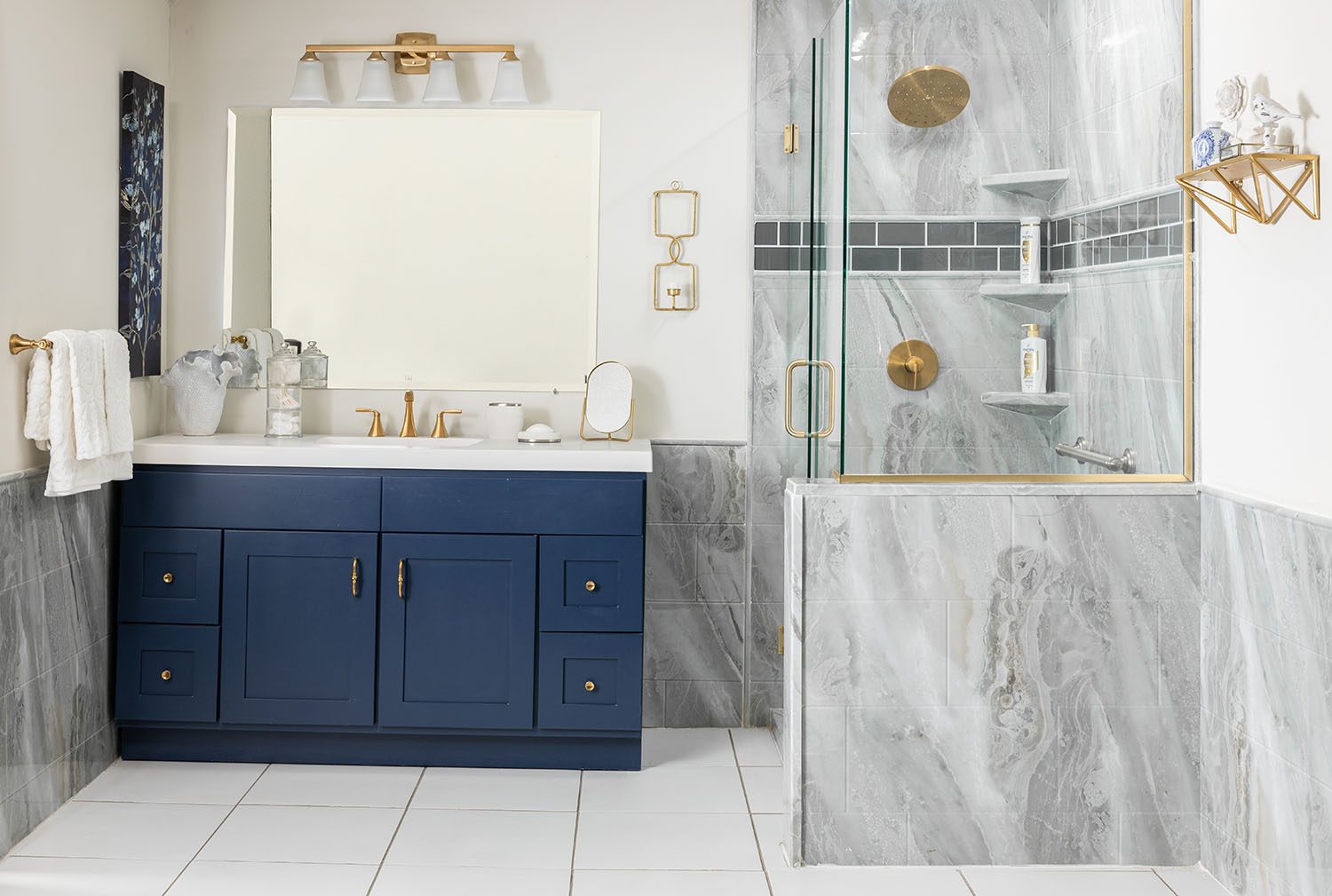 Bathroom remodeling Austin featuring remodeled bathroom with navy vanity, gold fixtures, marble tile, and glass shower