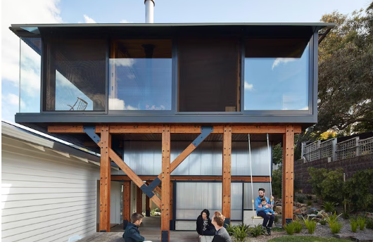 Home addition austin tx featuring a modern two-story Austin home with large glass windows and exposed wooden beams