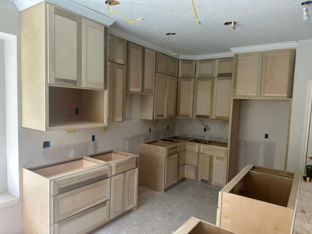 Kitchen remodeling company Austin showcasing L-shaped unfinished kitchen cabinets installed in a room under construction
