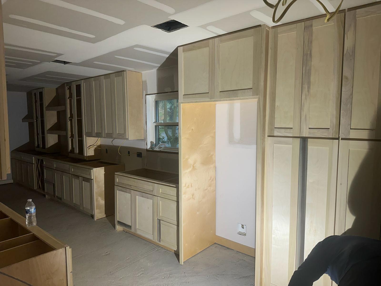 Kitchen remodeling company Austin showcasing Austin kitchen remodel with unfinished cabinets, open shelving, and exposed drywall