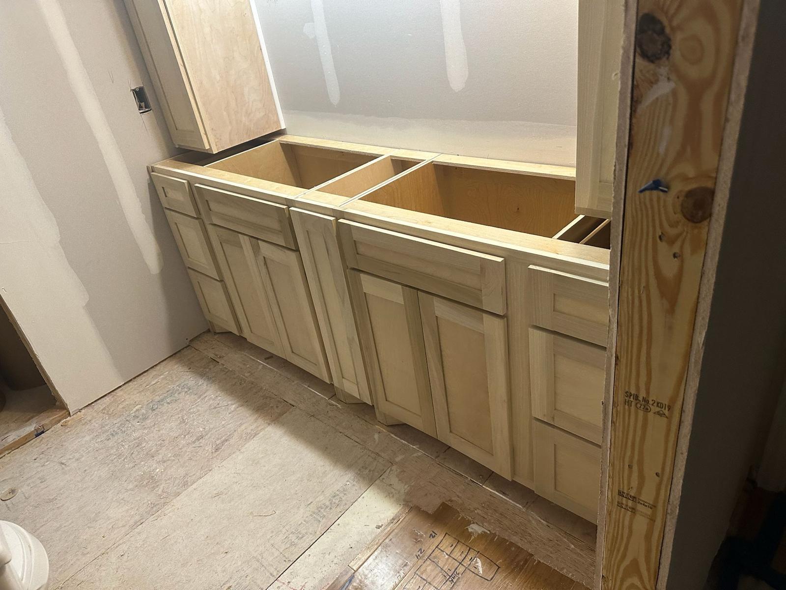 Kitchen remodeling company Austin showcasing unfinished kitchen cabinets installed with exposed drywall and floor during active renovation