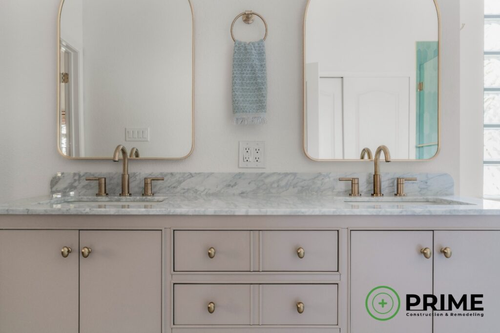 Bathroom remodeling Austin TX close-up view of a remodeled bathroom vanity with marble countertop, brass faucets, and arched mirrors in a modern renovation